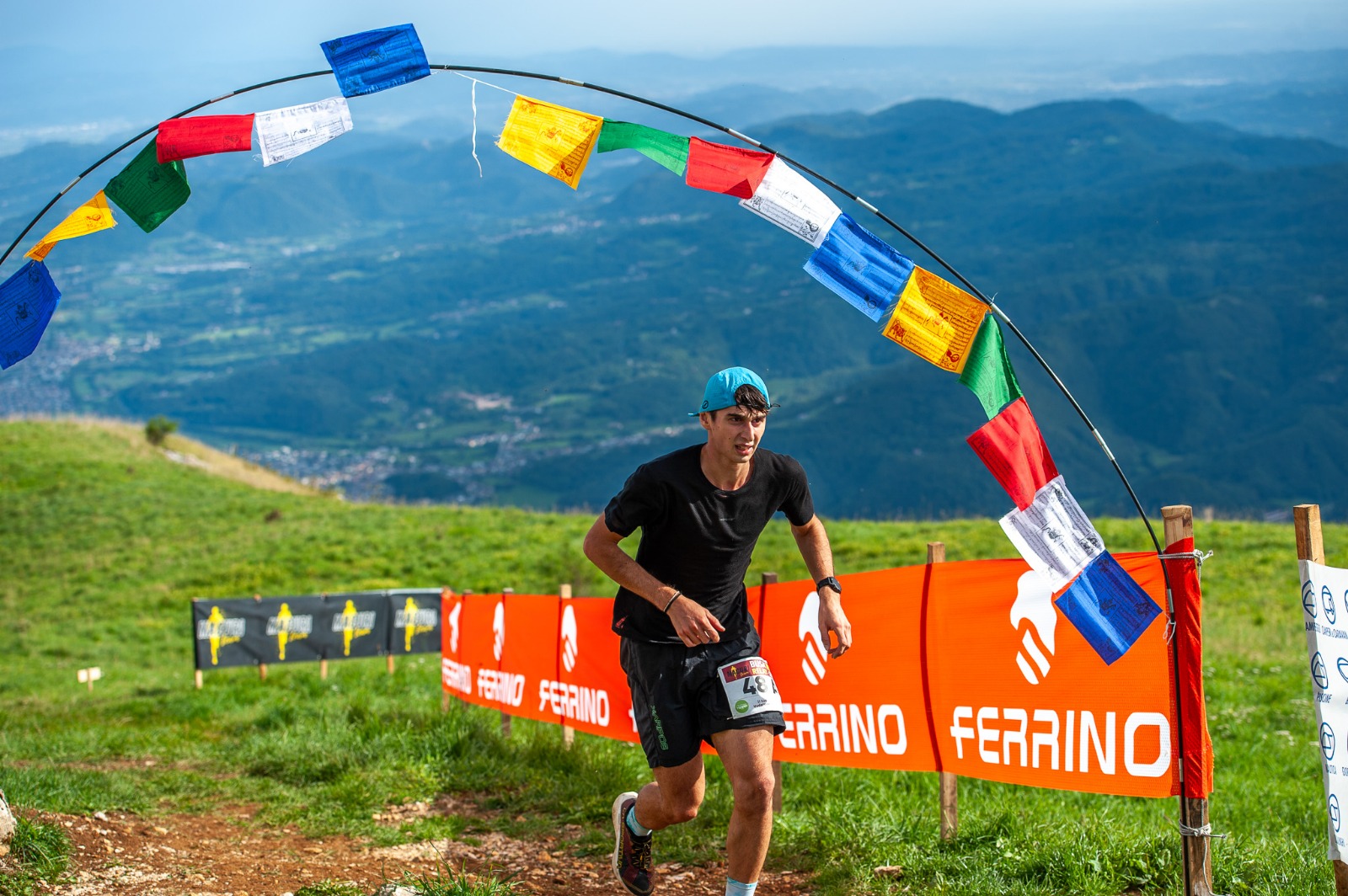Atleta sotto l'arco di bandiere tibetane al traguardo del Busa Trail Relay 2025